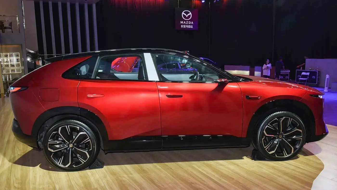 Mazda EZ-60 สีแดงมุมข้างเต็มคัน เห็นเส้นหลังคาลาดและมือจับประตูแบบฝังเรียบ