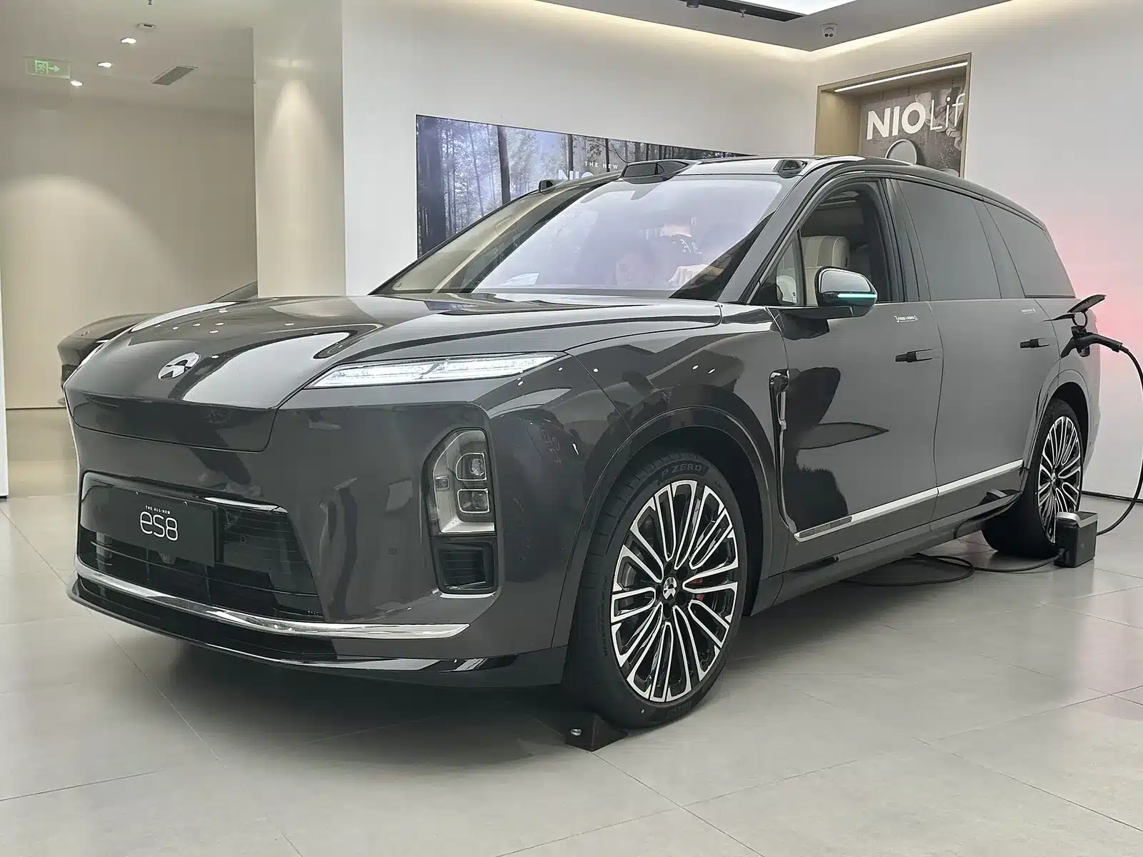 Nio ES8 เจเนอเรชันที่สามสีเทาเข้มจอดในโชว์รูม เห็นมุมหน้าสามส่วนสี่และไฟหน้าแบบแยกชั้น