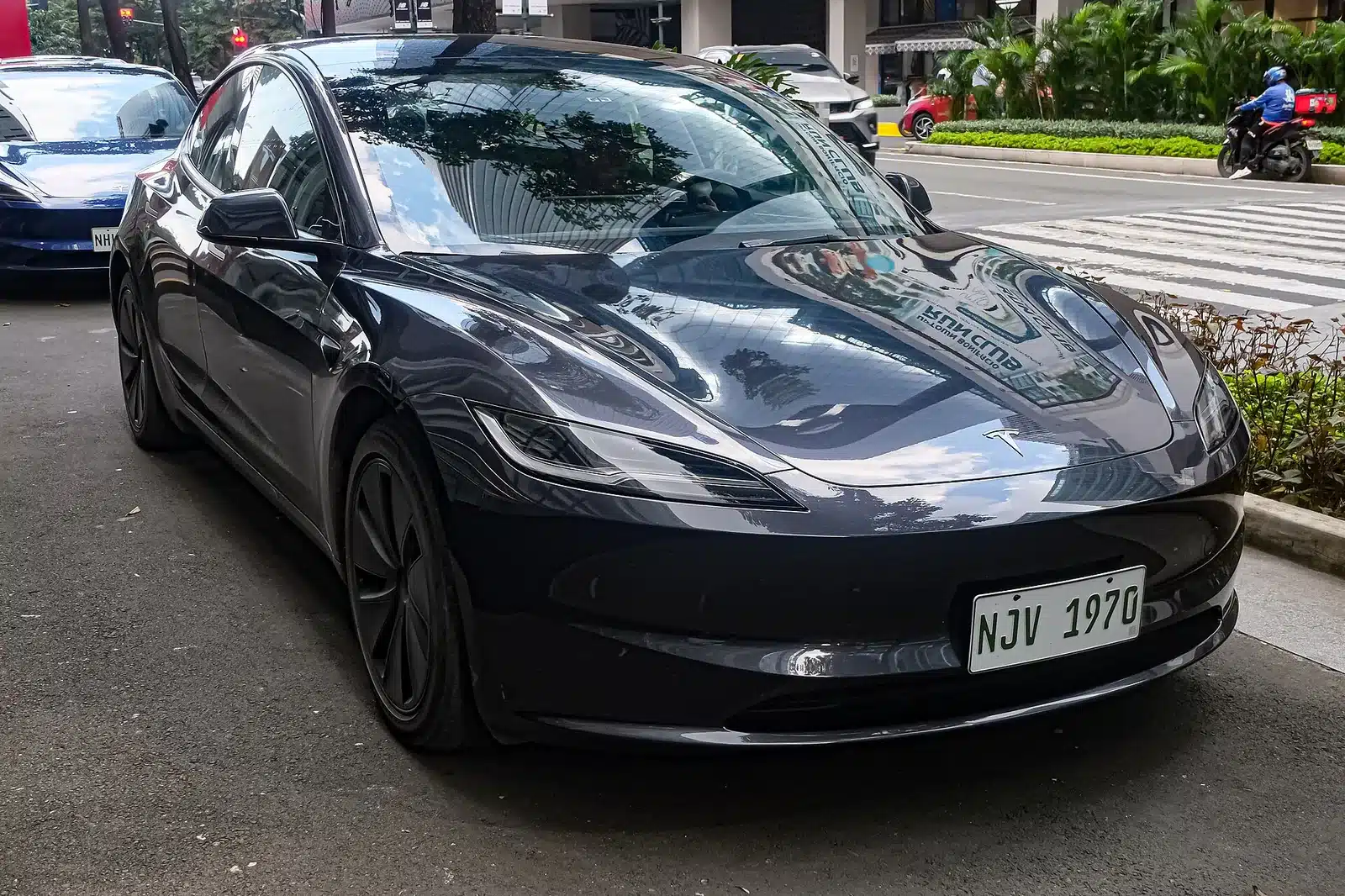 Tesla Model 3 สีดำมุมหน้าขณะจอดริมถนน