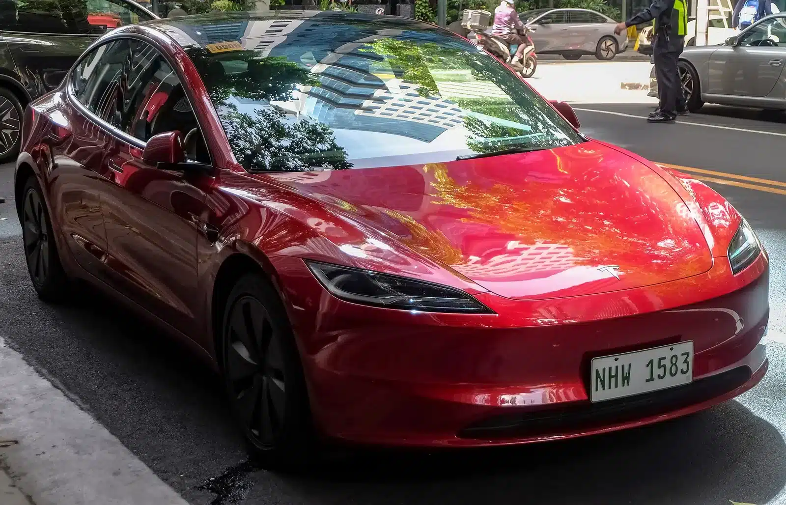 Tesla Model 3 สีแดงมุมหน้าบนถนนจริง